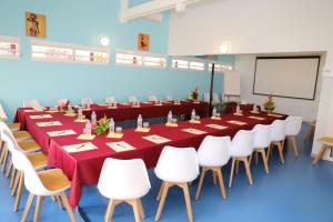 una gran sala de conferencias con una mesa larga y sillas blancas en Hôtel Saint-Georges en Saint-Claude