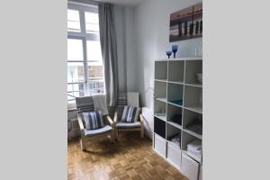 a room with two chairs and a book shelf at Central, Modern, mit großem Balkon Checkin123 in Wiesbaden