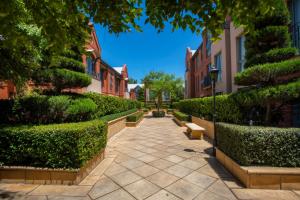 a walkway between some bushes and some buildings at Majestic Old Lion Apartments in Adelaide