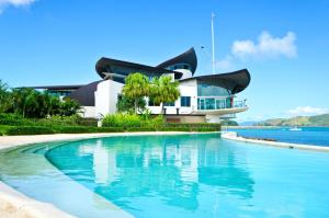 a house with a swimming pool in front of a building at Yacht Club Villas in Hamilton Island