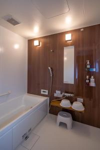 a bathroom with a tub and a toilet and a mirror at Obama Machiya Stay in Obama