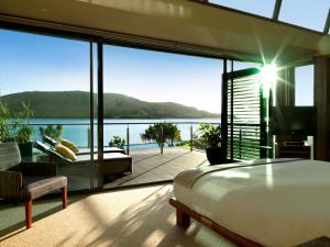 a bedroom with a bed and a view of the ocean at Yacht Club Villas in Hamilton Island