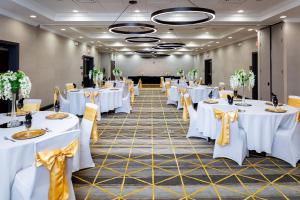 a banquet hall with white tables and yellow bows at Holiday Inn Statesboro-University Area by IHG in Statesboro