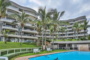 a large apartment building with a swimming pool and palm trees at 504 Ballito Manor View-Luxury home on the main beach in Ballito
