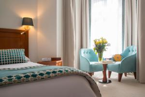 a bedroom with a bed and two chairs and a table at Hotel Olympia in Beausoleil