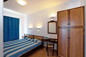 a bedroom with a bed and a desk and a cabinet at Katikies Studios & Apartments in Lardos