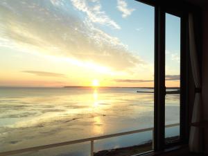 Lake Saroma Tsuruga Resort في كيتامي: منظر من نافذة على المحيط عند غروب الشمس