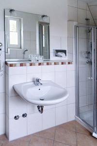 a white bathroom with a sink and a shower at Flair-Hotel Neeth in Lehmkuhlen