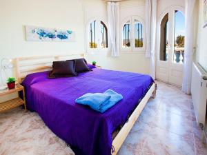 エンプリアブラバにあるHoliday Home Requesens canalの大型ベッド(紫のシーツ付)