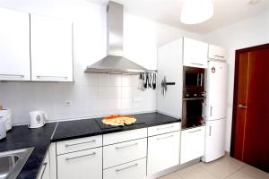 une cuisine avec des armoires blanches et un comptoir noir dans l'établissement Villa Emma Playa Blanca, à Playa Blanca