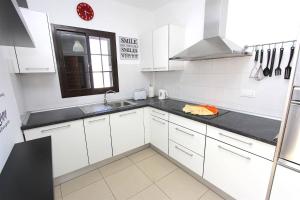 une cuisine avec des armoires blanches, un évier et une fenêtre dans l'établissement Villa Emma Playa Blanca, à Playa Blanca