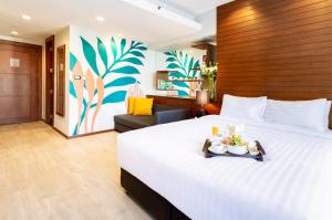 um quarto de hotel com uma cama grande com uma bandeja de comida em FuramaXclusive Sathorn, Bangkok em Bangkok