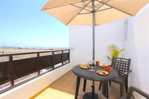 a small table with an umbrella on a balcony at Villa Emma Playa Blanca in Playa Blanca