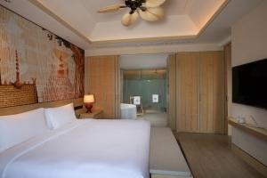 sypialnia z białym łóżkiem i wentylatorem sufitowym w obiekcie Angsana Xishuangbanna w mieście Menghai
