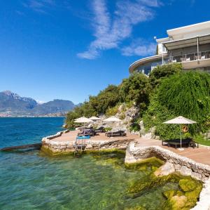 a beach with chairs and umbrellas in front of a building at Villa Tempesta in Nago-Torbole
