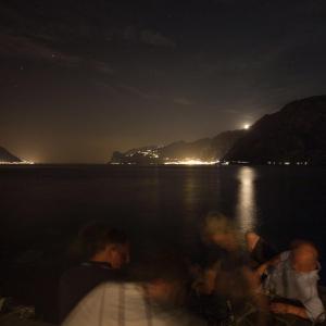 um grupo de pessoas sentadas em um barco na água à noite em Villa Tempesta em Nago-Torbole