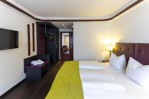 a hotel room with a bed and a flat screen tv at Hotel Gloria in Stuttgart