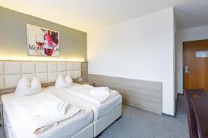 ein Hotelzimmer mit einem großen Bett mit weißen Kissen in der Unterkunft Bavaria Hotel Münchner Hof Superior in Stuttgart