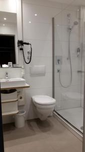 
a white toilet sitting next to a shower in a bathroom at Hotel Gloria Superior in Stuttgart
