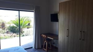 Schlafzimmer mit einem Bett, einem Schreibtisch und einem Fenster in der Unterkunft Oubaai Ocean View Private Self catering rooms Herolds Bay in George