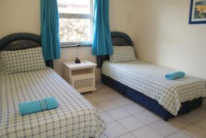 a bedroom with two beds with blue curtains and a window at Rosscarbery 6 in Margate