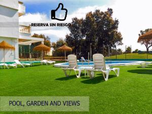 two chairs and a table in the grass near a swimming pool at Roquetas Beach and Playa Serena Golf Village in Roquetas de Mar