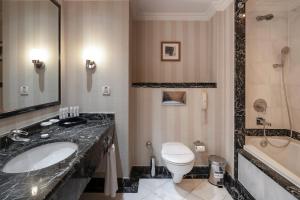 a bathroom with a sink and a toilet and a tub at Asteria Kemer Resort in Kemer