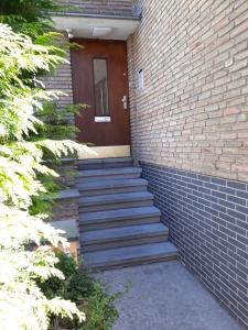 Un escalier mène à un bâtiment en briques avec une porte brune. dans l'établissement Apartment Jackie 2, à Bielefeld