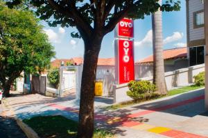 a red stop sign on a pole next to a tree at OYO Cerrado Hotel, Campo Grande in Campo Grande