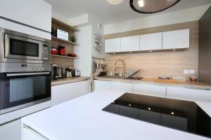 a kitchen with white cabinets and a microwave oven at expat renting - Le Mosaïque - Patte d'Oie - Parking in Toulouse