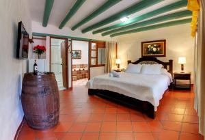 a bedroom with a large bed and a wooden barrel at Hotel Spa Villa Lina in Villa de Leyva