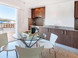a kitchen with a glass table and white chairs at Apartment Blue Ocean-3 by Interhome in Llança