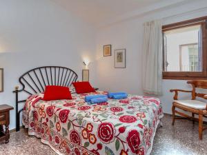 Un dormitorio con una cama con almohadas rojas y una silla en Apartment Can Panxo by Interhome, en L'Escala