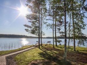 a picnic table and bench on the shore of a lake at Holiday Home Suvituuli by Interhome in Pertunmaa