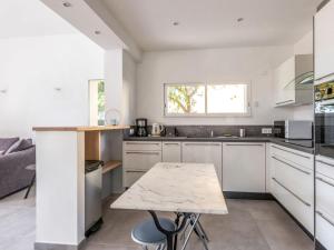 eine Küche mit weißen Schränken und einem Tisch in der Unterkunft Villa Mont des oiseaux by Interhome in Toulon
