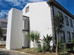 un bâtiment blanc avec une porte et quelques plantes dans l'établissement Azores Youth Hostels - Sao Miguel, à Ponta Delgada