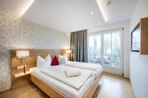a bedroom with a large bed and a large window at Appartementhotel Röhrenbach in Immenstaad am Bodensee