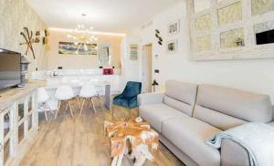 トレモリノスにあるApartamentos LOLA y MANUELA en primera línea playa Carihuela con excelente Terraza-jardin de 80 m2 frente al Mar con aparcamiento privado Ideal para descansar oyendo las olas del Marの白いソファとキッチンのあるリビングルーム