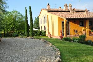 a yellow house with a gravel driveway at La Corte D'Elsa in Castelfiorentino