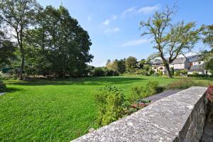 a garden with a stone wall and a grass field at Hotel Le Saint Hadelin in Celles