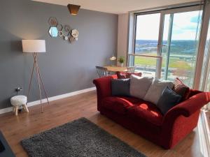 a living room with a red couch and a large window at Tailor That Property - Chelsea House in Milton Keynes