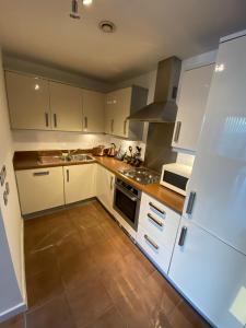 een keuken met witte kasten en een fornuis met oven bij Tailor That Property - Chelsea House in Milton Keynes