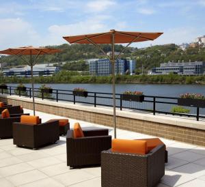 a patio with chairs and umbrellas and a river at HYATT House Pittsburgh-South Side in Pittsburgh