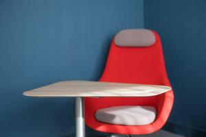 a red chair sitting next to a desk with a table at Holiday Inn Express Amsterdam - North Riverside by IHG in Amsterdam