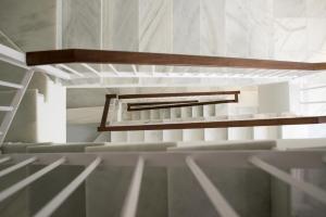 Una habitación vacía con paredes blancas y escaleras de madera. en La Posada del Mercado, en Cádiz