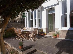 a patio with a table and chairs in front of a house at Myrtle House Penzance in Penzance