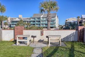 2 Picknicktische und ein Gebäude mit Palmen in der Unterkunft Lei Lani Tower by Meyer Vacation Rentals in Orange Beach