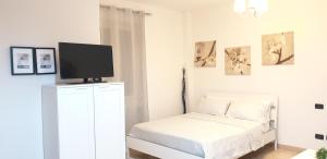 een witte slaapkamer met een bed en een tv op een dressoir bij Philips apartment in Milaan