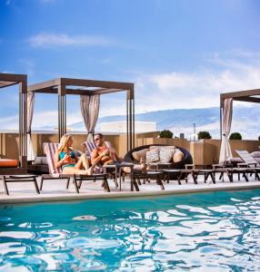a group of people sitting on lounge chairs next to a swimming pool at Silver Legacy Reno Resort Casino at THE ROW in Reno