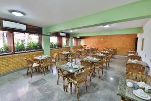 an empty restaurant with tables and chairs and windows at Pousada da Ladeira in Pipa
